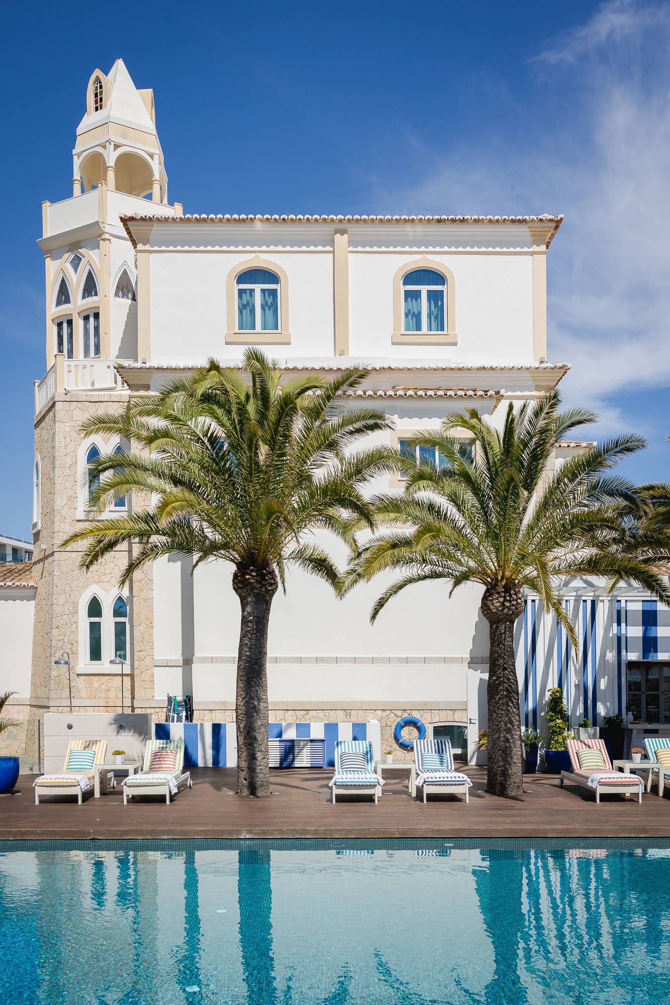 <p>Membro da prestigiada Relais & Châteaux desde 2013, este boutique hotel de 5 estrelas é um projeto que alia o design e os serviços da hotelaria de excelência ao charme da história do século XX.</p>
<p>&nbsp;</p>
<p>Passando pelo portão de ferro forjado, entro no belo recinto do deslumbrante palacete Belle Époque. A sua fachada branca brilha contra o fundo de céu azul real e de repente encontro-me envolto em silêncio e tranquilidade.</p>
<p>&nbsp;</p>
<p>Atrás de mim, além do portão, deixei os letreiros de néon dos Sports Bars, Irish Pubs e o betão dos prédios da Avenida Tomás Cabreira, a eternamente agitada “strip” de Portimão.</p>
<p>&nbsp;</p>
<p>Na receção, recebo a chave para o #102, um amplo quarto de canto do próprio palacete com vista para o mar, um terraço e – na balaustrada deste – uma gaivota aparentemente residente.<br />
É um dos 38 quartos do hotel espalhados entre o palacete, a neoclássica “Casa Azul” e a nova ala “Jardim” que também abriga o Spa by L’Occitane – um de só três em Portugal que têm o nome da marca francesa. Com 400 m2, tem cinco salas de tratamento, sauna, banho turco e uma zona húmida de relaxamento dotada de uma “plunge pool”.</p>
<p>&nbsp;</p>
<p>Ao lado, um ginásio completo com 100 m2 a dois passos da piscina exterior que, rodeada de palmeiras, convida com um ambiente exótico, porém civilizado (as espreguiçadeiras estão bem espaçadas e o pessoal do bar da piscina é atencioso mas discreto).</p>
